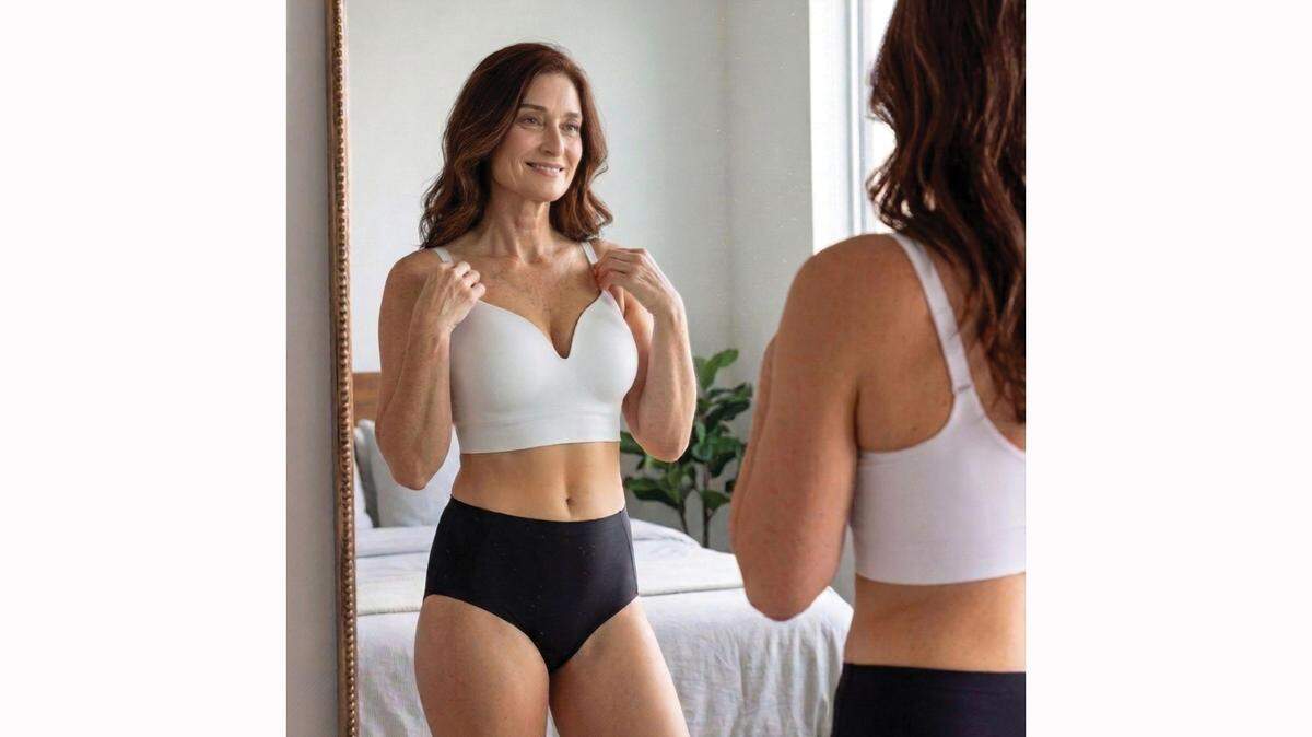 Woman checking bra fit and posture in a mirror for comfort.