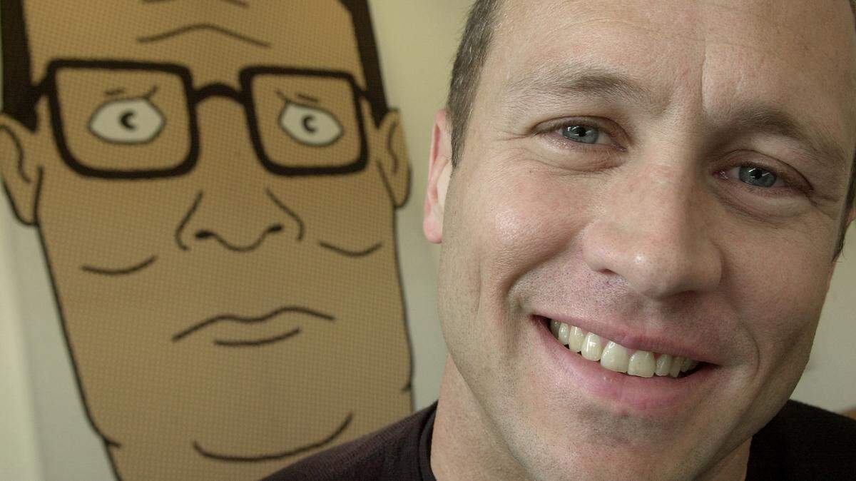 **FILE**Mike Judge, co-creator of the Fox cartoon series “King of the Hill,” poses in front of an illustration of Hank Hill, the animated character he voices, in this Oct. 28, 2002, file photo made in Los Angeles. It was recently announced that “King of the Hill” will return as a streaming series in 2023. (AP Photo/Ric Francis, FILE)