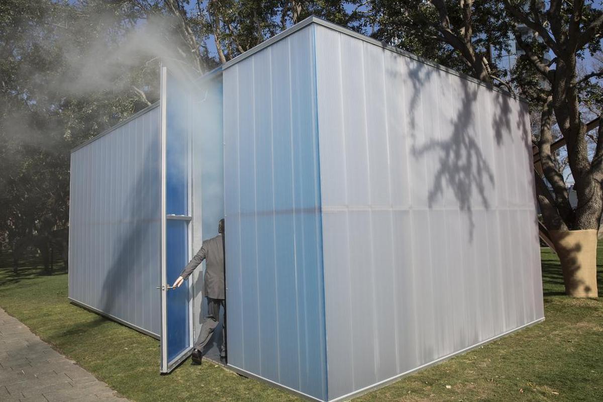 Fog escapes as a man enters “Blue, Red and Yellow” by artist Ann Veronica Janssens.