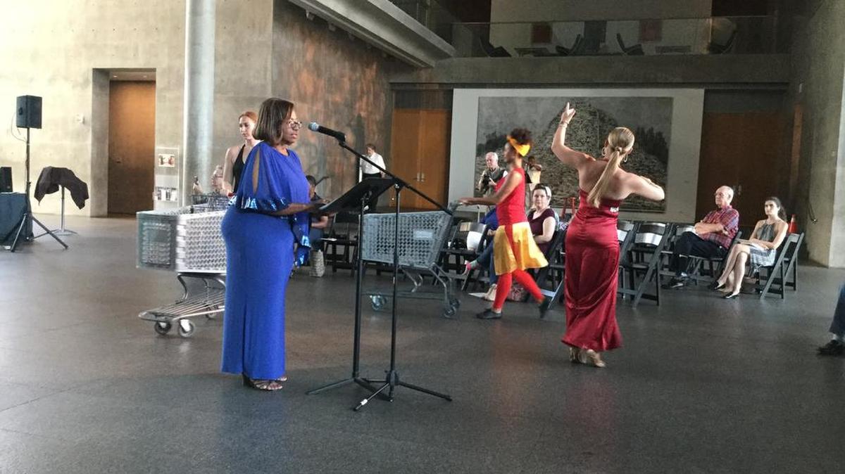 Charlece Thomas-James reads while dancers from Contemporary Dance/Fort Worth perform in the Grand Lobby of the Modern Art Museum of Fort Worth