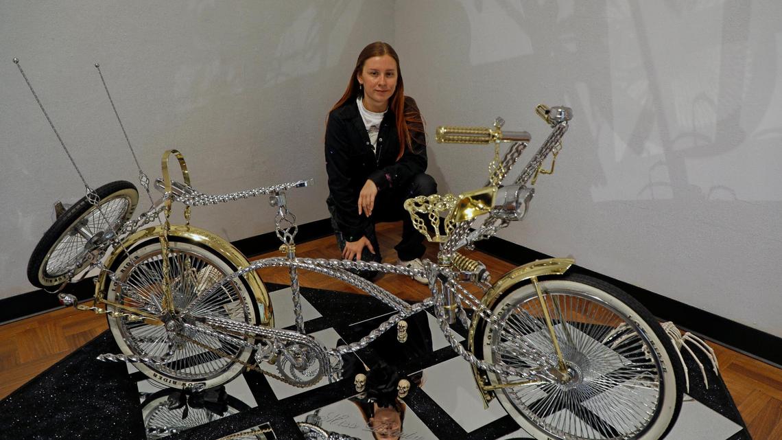 Fort Worth artist Sarah Ayala with one of the bicycles featured in “Adelante: Puro Raza Bicycle and Pedal Car Show” at the Fort Worth Community Arts Center.