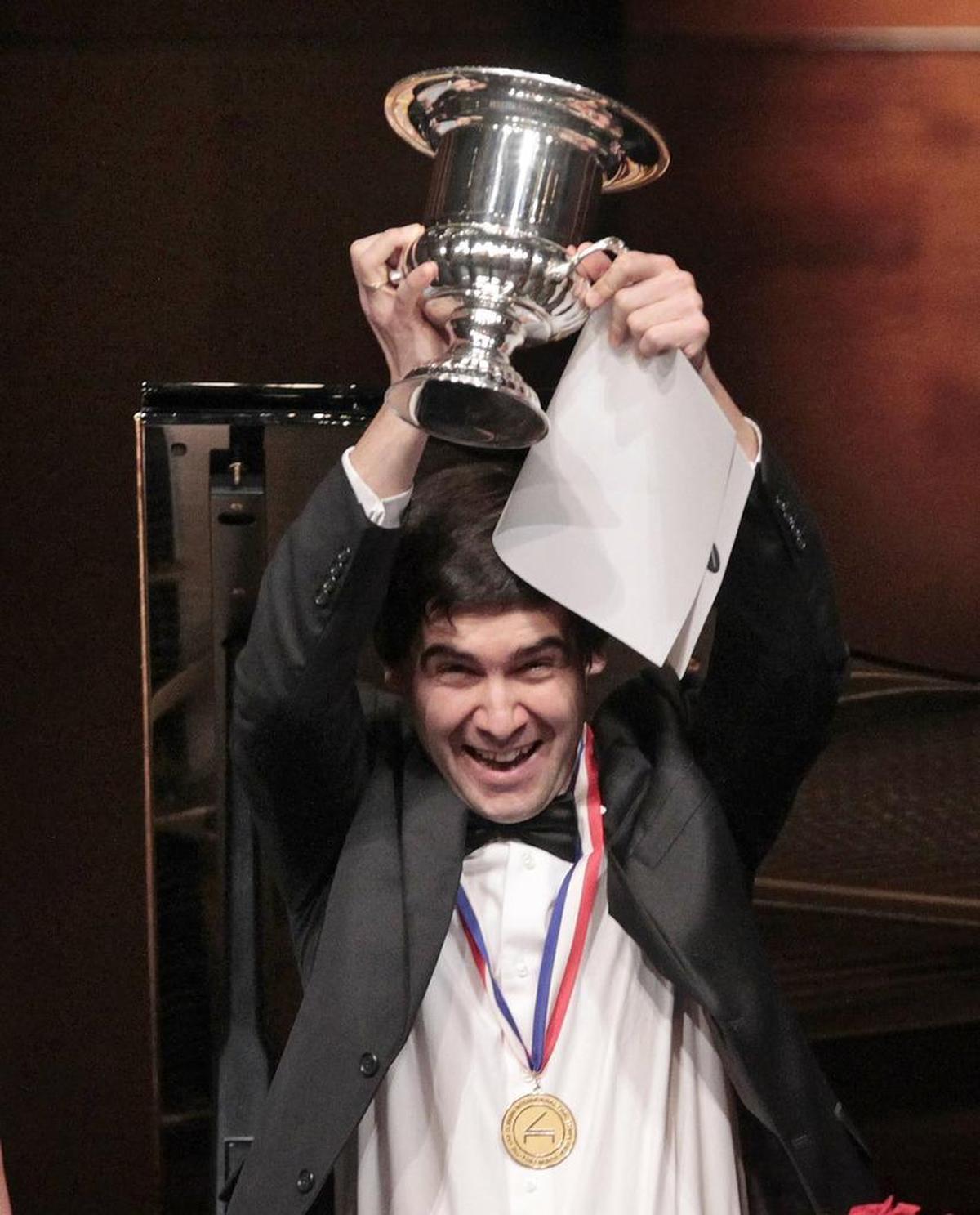 Kholodenko wears the gold medal and hoists the winner’s cup after winning the 14th Van Cliburn International Piano Competition in Fort Worth.