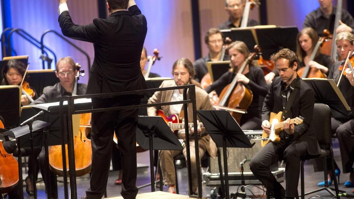The Dallas Symphony Orchestra, conducted by Brett Mitchell, and Travis Andrews and Bryce Dessner (on electric guitars) perform Bryce Dessner’s composition “St. Carolyn by the Sea” on March 12, 2016 at Dallas City Performance Hall.