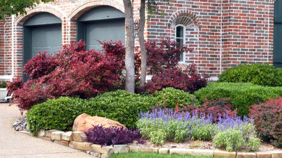 Clusters of attractive plants carefully chosen and placed blend well against red-toned brick.
