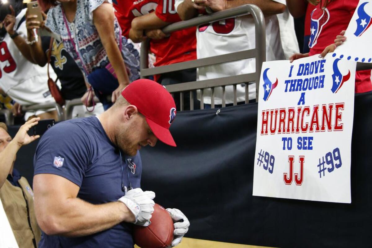 Houston Texans defensive end J.J. Watt signs autographs for fans holding sings referencing Hurricane Harvey before an NFL football game at the New Orleans Saints.