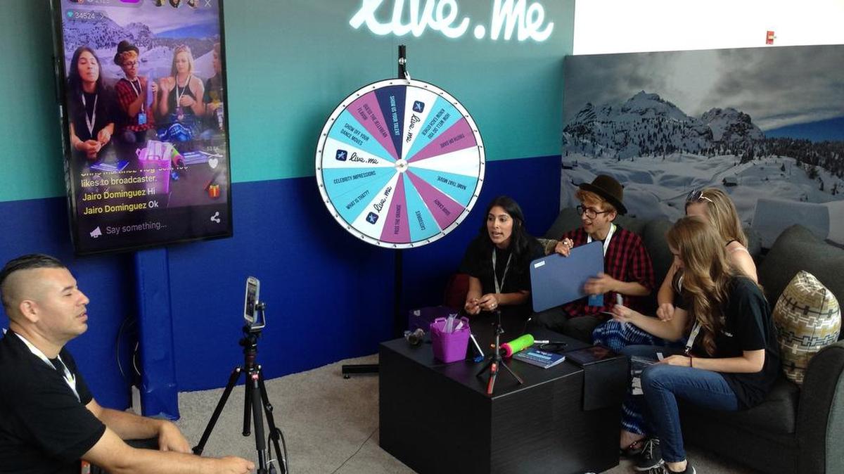 In this June 23, 2016, photo, Erick Armas, left, captures video of, from right, Jordan Hoyle, Violet Summersby, George Padilla and Sue Evelyn Gil, who were live broadcasting from the live.me booth at VidCon, an annual convention for the fans of stars from YouTube, Vine, Instagram and other video platforms, at the Anaheim Convention Center in Anaheim, Cailf.