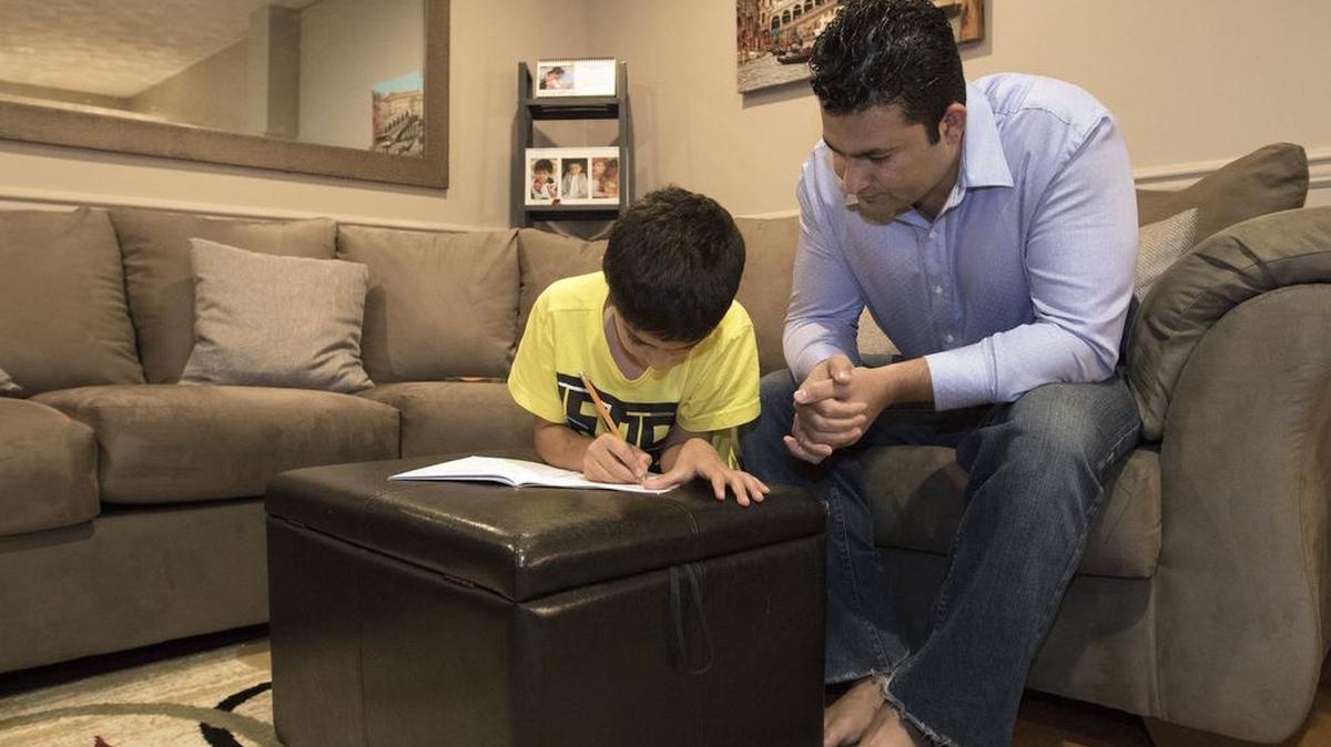 Mirwais Nasari, right, helps his 8-year-old son, Arian Nasari, with math before dinner in Springfield, Va.
