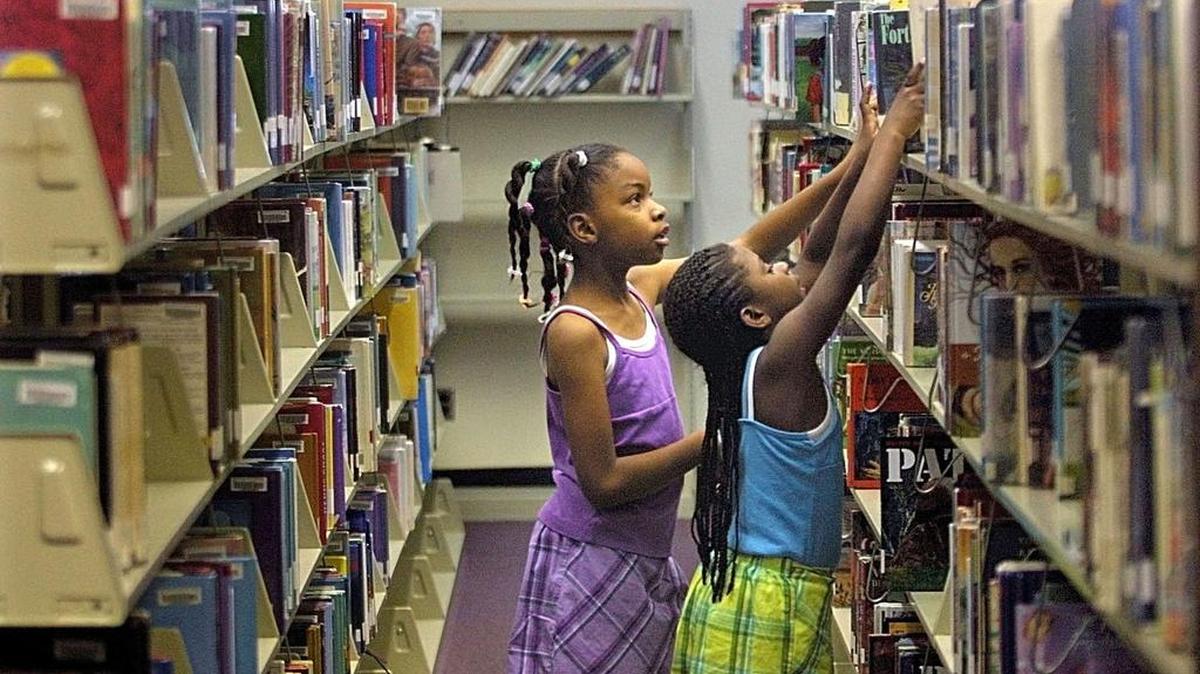 Calah Gowdy, left, and Kachita Barber search for a book to check out from the children’s department of the Bradley Library in Columbus, Georgia.