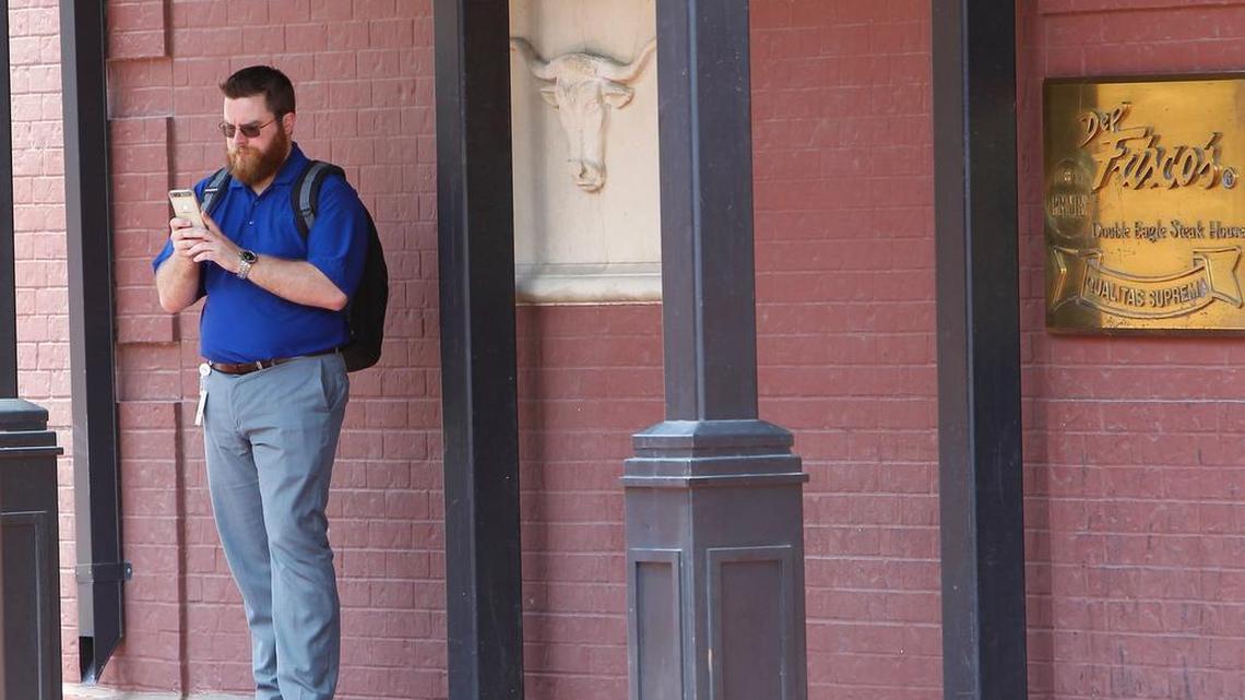“Pokemon GO” player Jace Lawler stops to check his phone on the sidewalk near Del Friscos in downtown Fort Worth.