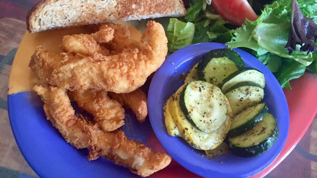 Spicy chicken tenders with zucchini and salad at Old Neighborhood Grill.