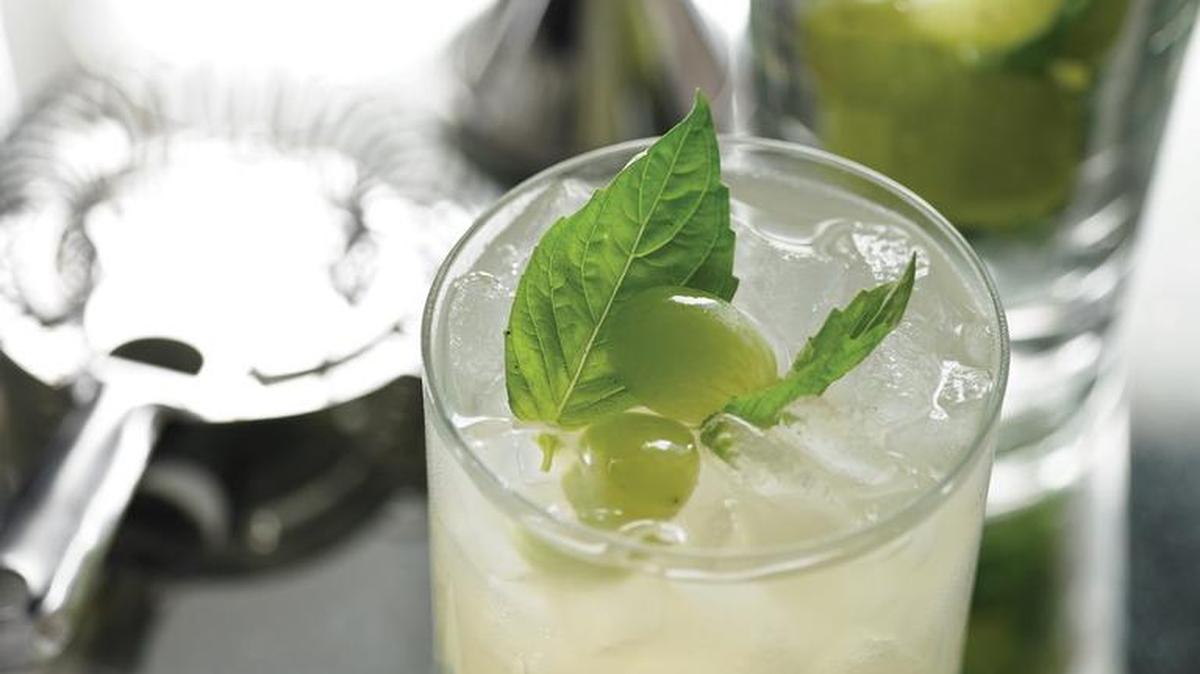 Top martinis with basil leaves and grapes.