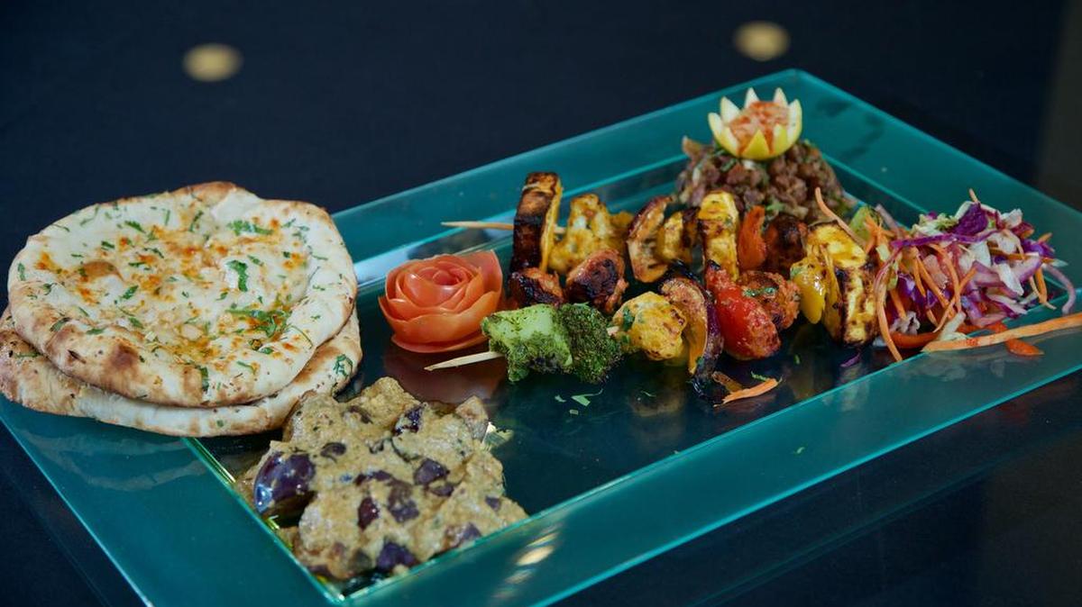 Garlic cilantro naan, top left, egg plant curry, bottom left, mixed vegetables, center of plate, and an Indian street food Chaat, back right, made with black beans at "Route 66" inside Radisson Hotel in South Fort Worth,