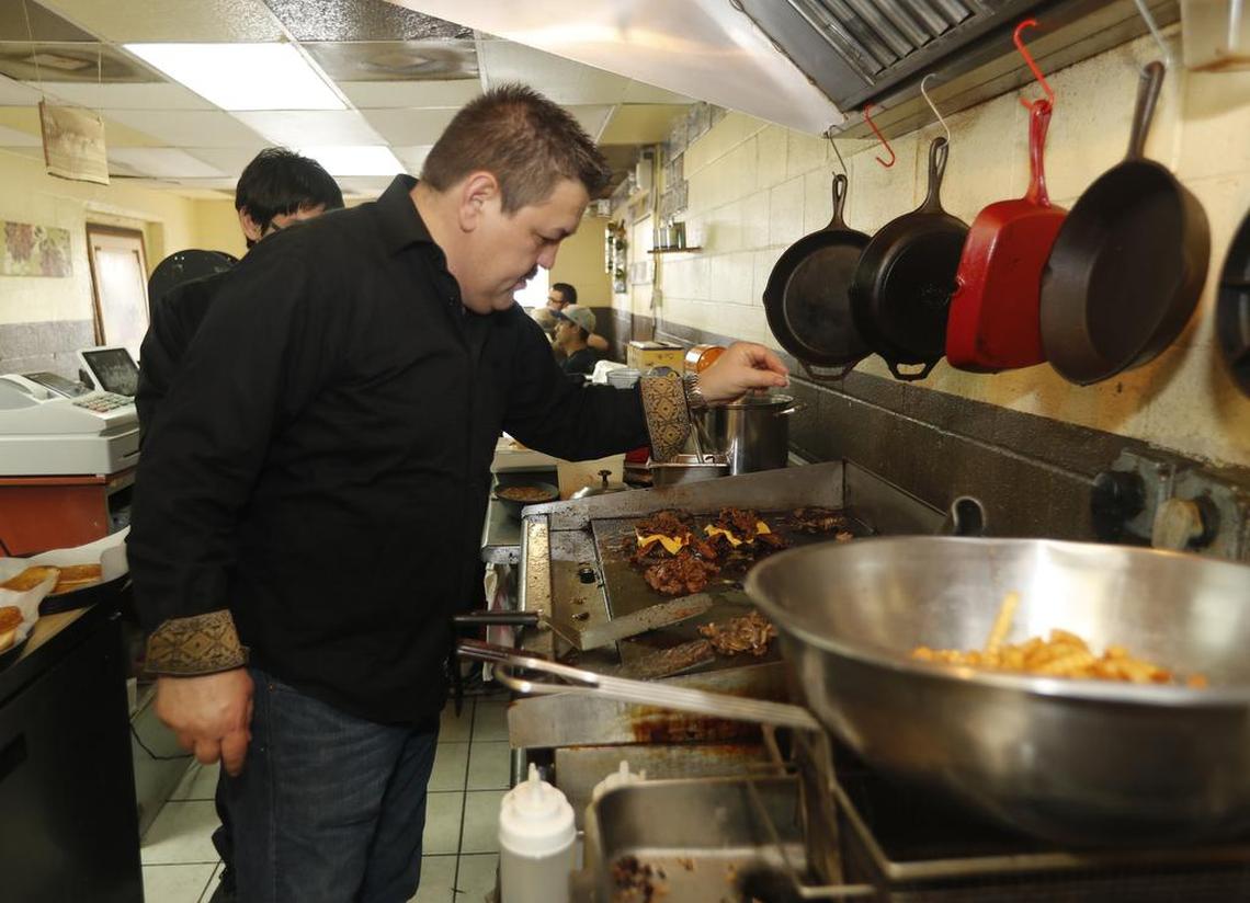 Carlos Rodriguez adds some spices to grilling burgers at Fuego Burger at the restaurant’s former Rendon location in this archive photo.