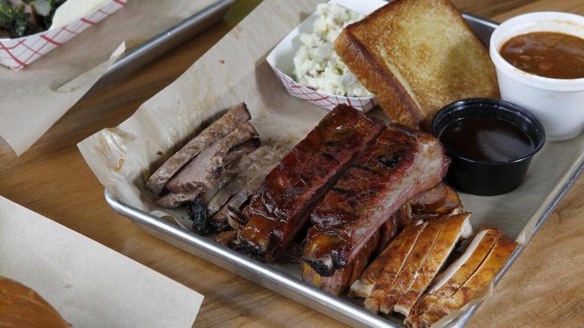 The Moo-Oink-En platter at Roscoe’s Smokehouse in Keller comes with sliced brisket, pork ribs, sausage and chicken