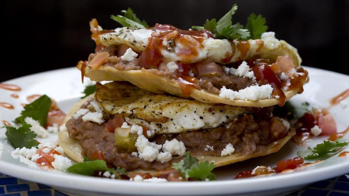 The Mexican short stack — stacked tostadas, refried beans, avocado, cheese with ranchero sauce and a fried egg — at West Fork Grill im Fort Worth