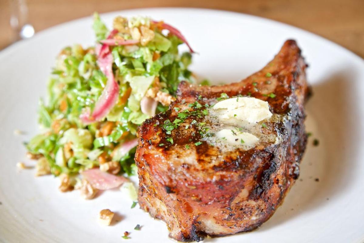 A pork chop and Brussels sprouts coleslaw at Cork & Pig Tavern in Fort Worth