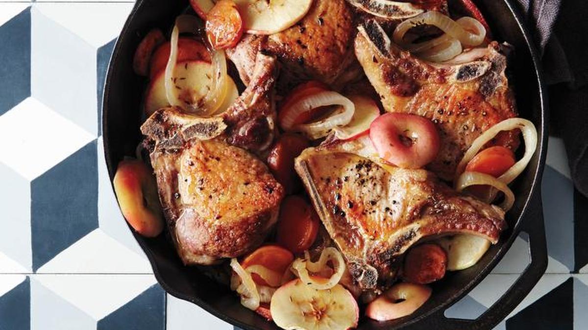 A seasoned cast-iron skillet transfers easily from stove top to oven. Here it holds juicy pork chops and built-in side dishes.
