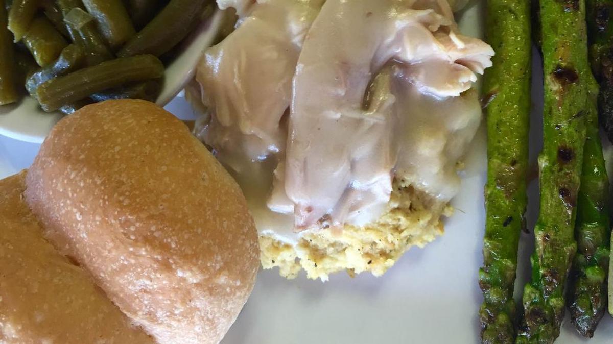 A turkey-and-dressing lunch at Arlington Steak House with yeast rolls and veggies.