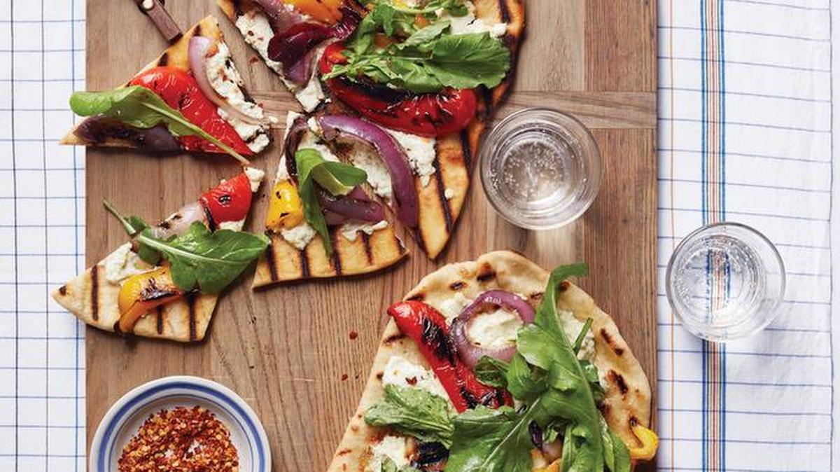 Think beyond the beef. This quick grilled pizza with peppers and onions on a bed of goat cheese has a delicate balance of acidity, sweetness and heat.