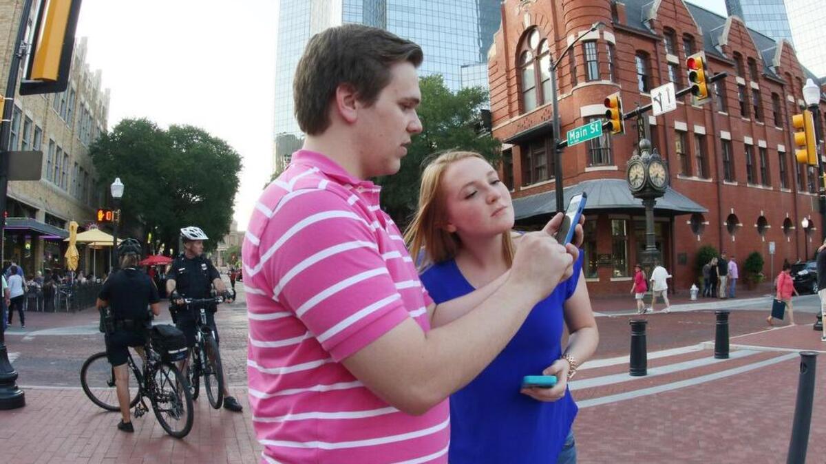 Carson Wright, 20, shows his sister Camryn, 14, how he captures an elusive Pokemon as they play Pokemon Go in Sundance Square.