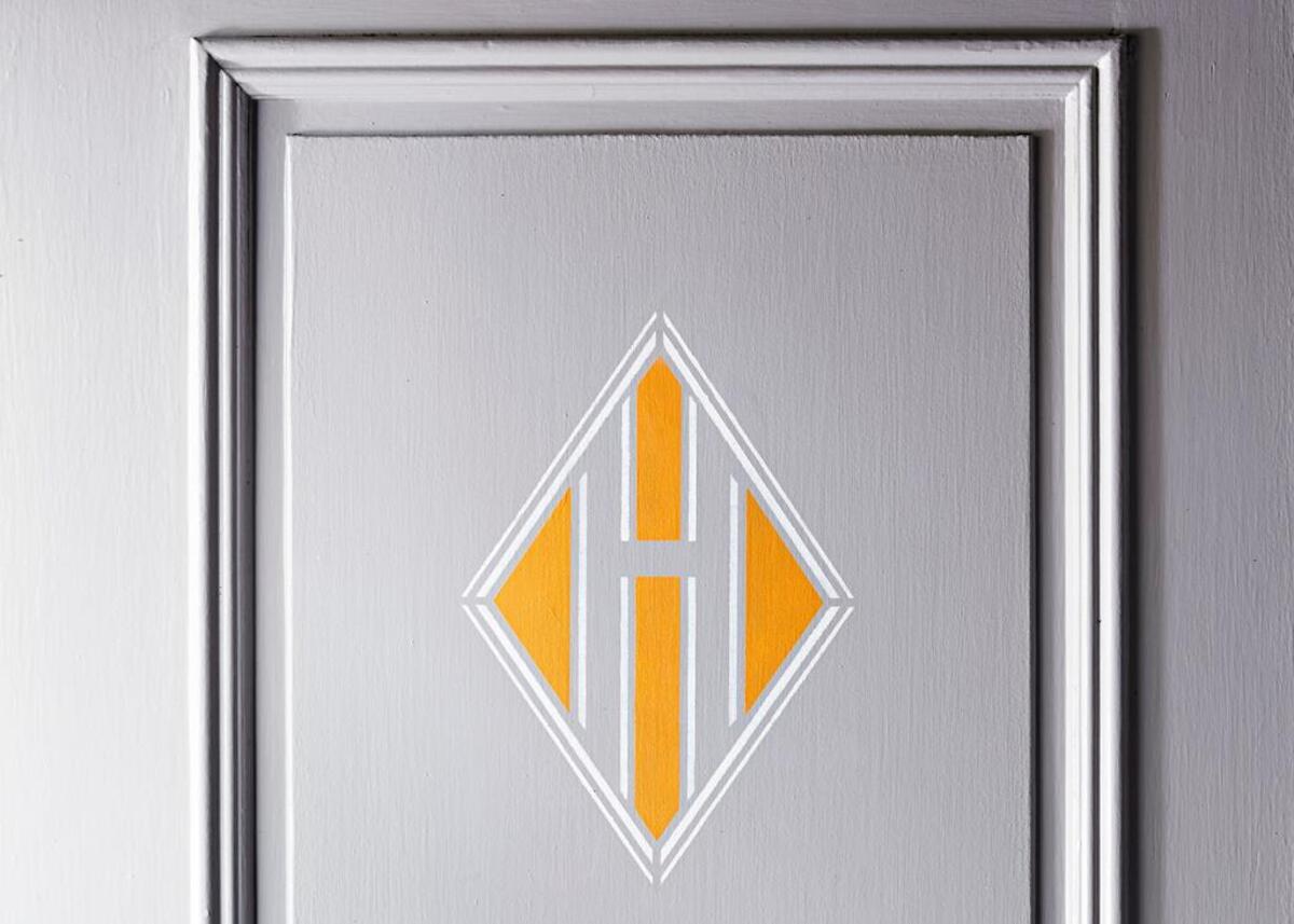 The marigold and white lines of this abstract, art deco–inspired design (a not-so-obvious letter H) stand out on a classic gray front door. .