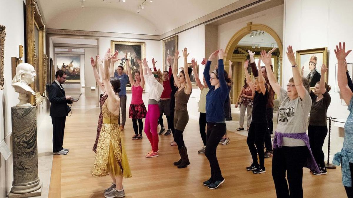 An exercise group works in front of a bust of Benjamin Franklin at the Metropolitan Museum of Art in New York.