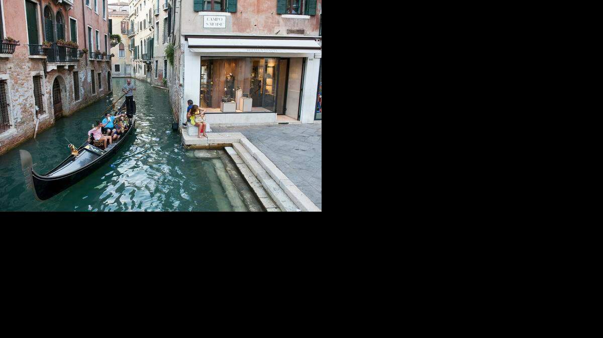 
A gondolier navigates his passengers along a canal near the luxury retail district in Venice, Italy. Illustrates VENICE-FAMILY (category t), by Paul Abercrombie, special to The Washington Post. Moved Tuesday, Dec. 2, 2014. (MUST CREDIT: Marco Secchi/Bloomberg.) 
