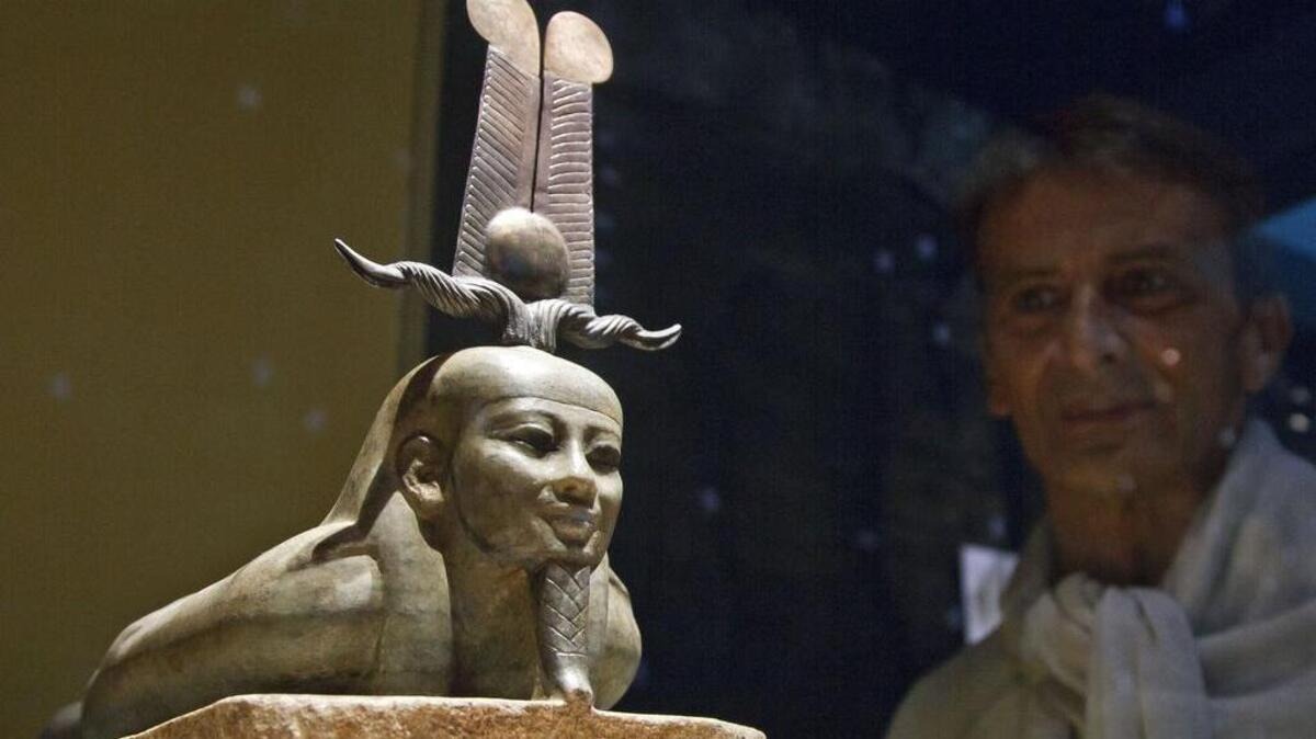 
A man looks at a bronze statue, the awakening of Osiris, 26th dynasty (665-525 BC), displayed at the Institut du Monde Arabe (Arab World Institute), part of the Osiris, Sunken Mysteries of Egypt exhibition in Paris, France. 
