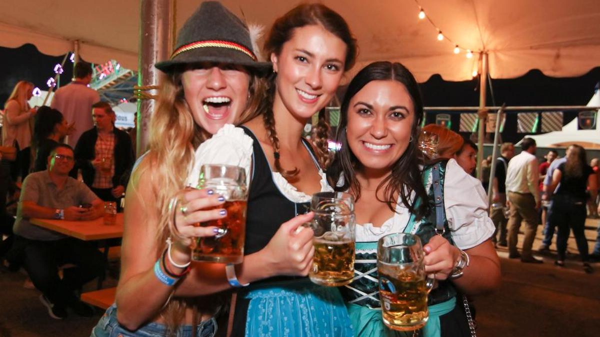 Three women holding glass beer mugs.