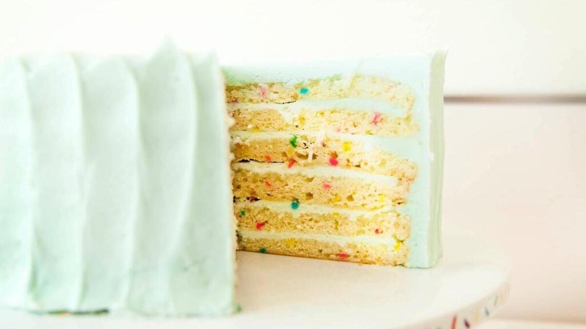 Vanilla Celebration Cake at SusieCakes is a six-layer cake with colored-sugar “confetti,” filled and frosted with “retro blue” vanilla frosting.