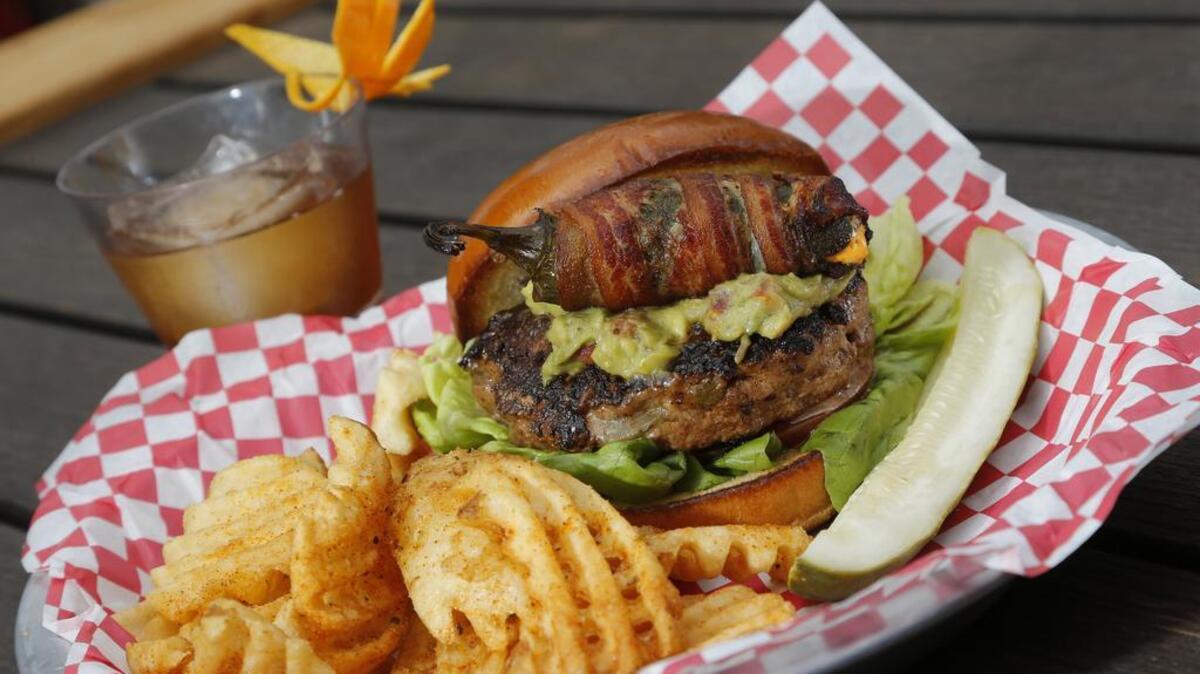 The jalapeño burger at America Gardens in Fort Worth: a Black Angus patty stuffed with roasted jalapeños and pepperjack, with butter lettuce, greenhouse tomatoes, guacamole and a jalapeño popper wrapped in bacon served on a brioche bun.