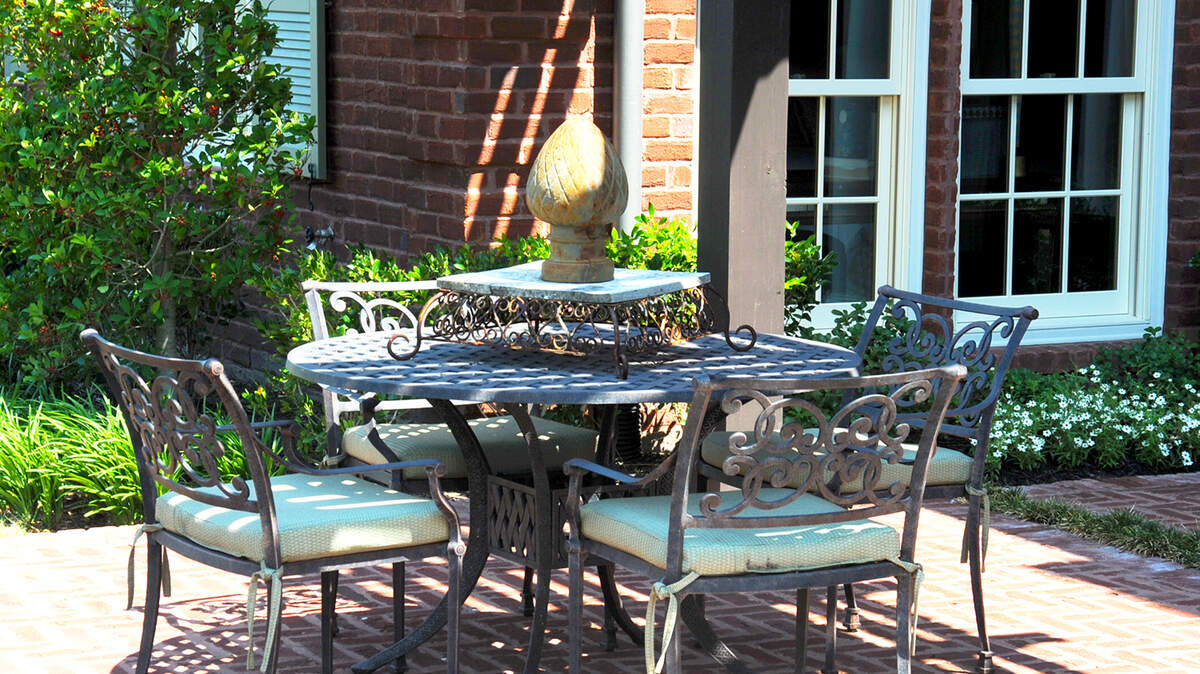 This patio setting is framed by its plants. For landscaping, keep the sequence of improvements in mind, especially for long-term projects.