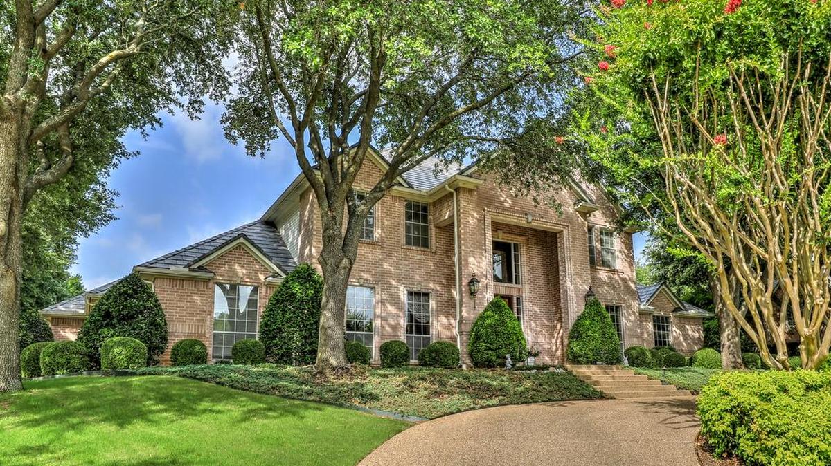 The home at 6108 Annandale Drive is located on a cul-de-sac with manicured landscaping and towering trees.