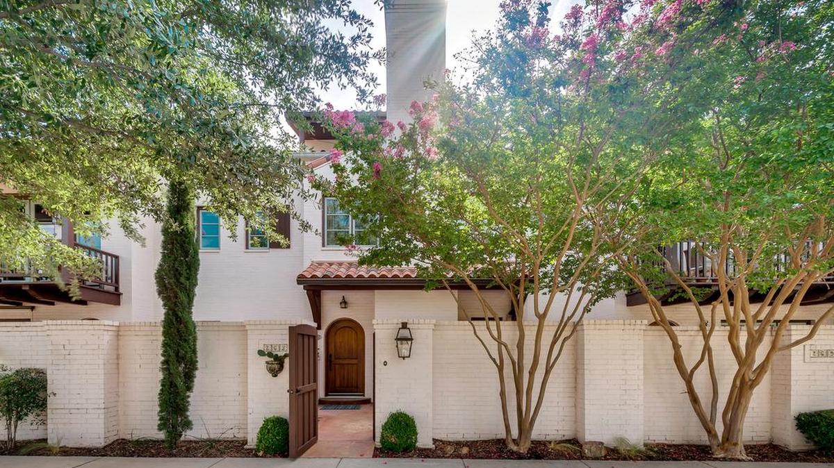 The home at 265 Casa Blanca Avenue features eye-catching trees, an arched entrance gate and Spanish details.