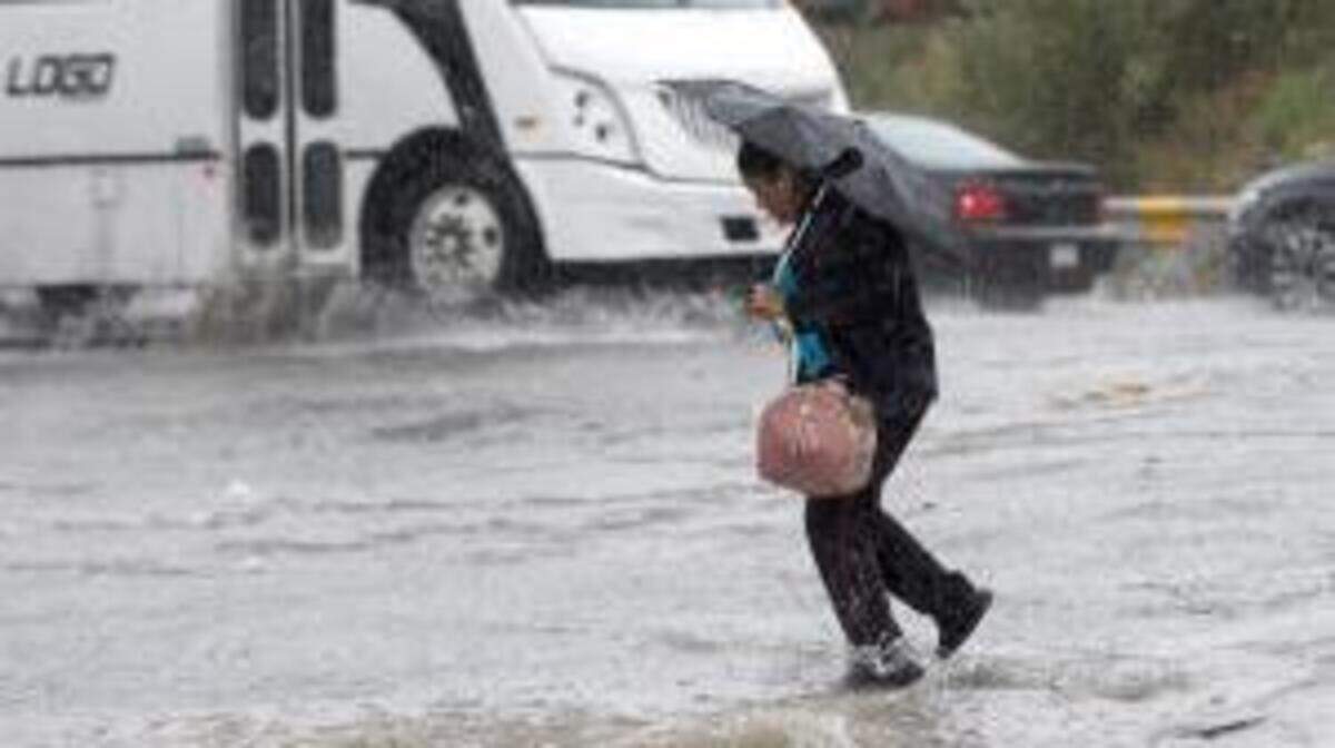 Una mujer cruza una calle inundada en Saltillo, Coahuila.