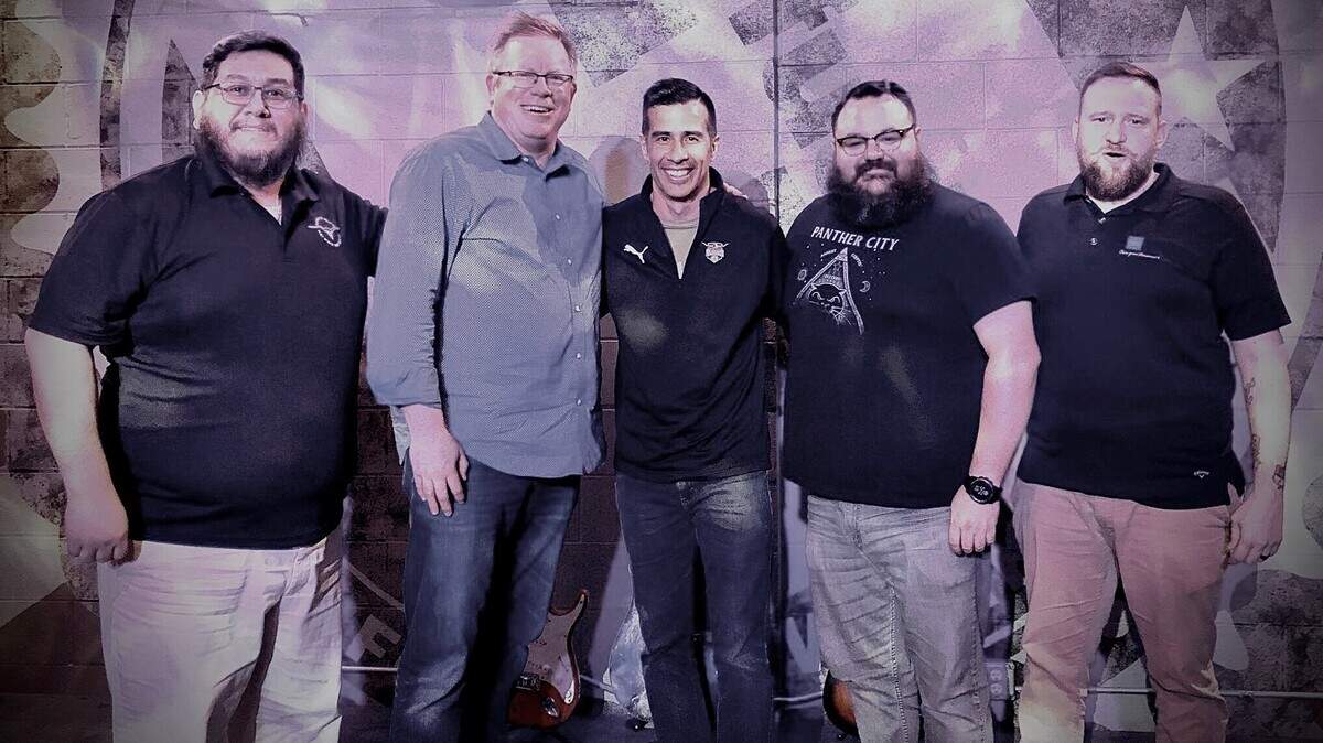 Michael Hitchcock (dueño, segundo de Izq.) y Anthony Harris (gerente general, centro), posan con representantes de la porra official de los Vaqueros, Panther City Hellfire.