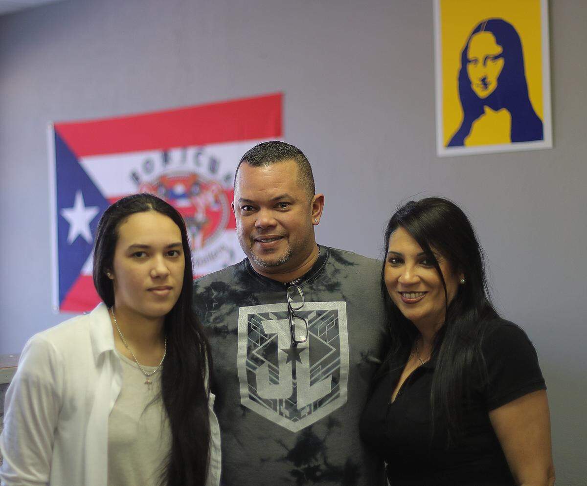 Wilfredo Colón posa con su hija Paola y su esposa Carmen en su estudio de tatuajes, llamado Latinos Tattoo.