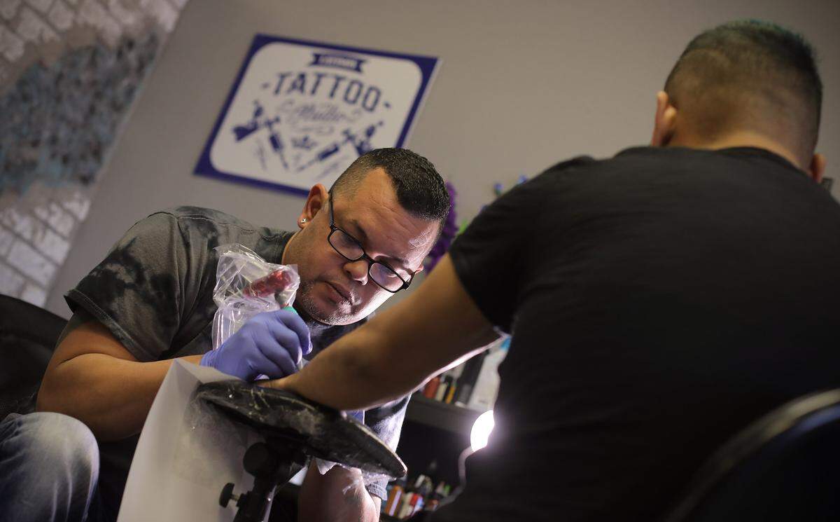 Wilfredo Colón trabaja en un tatuaje para Arturo Escalona en su estudio en Benbrook.
