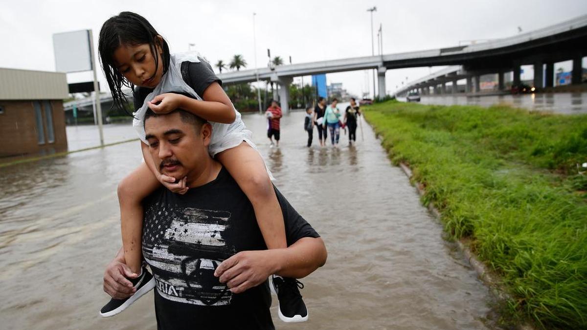Jesús Núñez carga a su hija Génesis, de 6 años, después de que él y varios familiares abandonaron su casa que fue inundada por la tormenta Harvey.