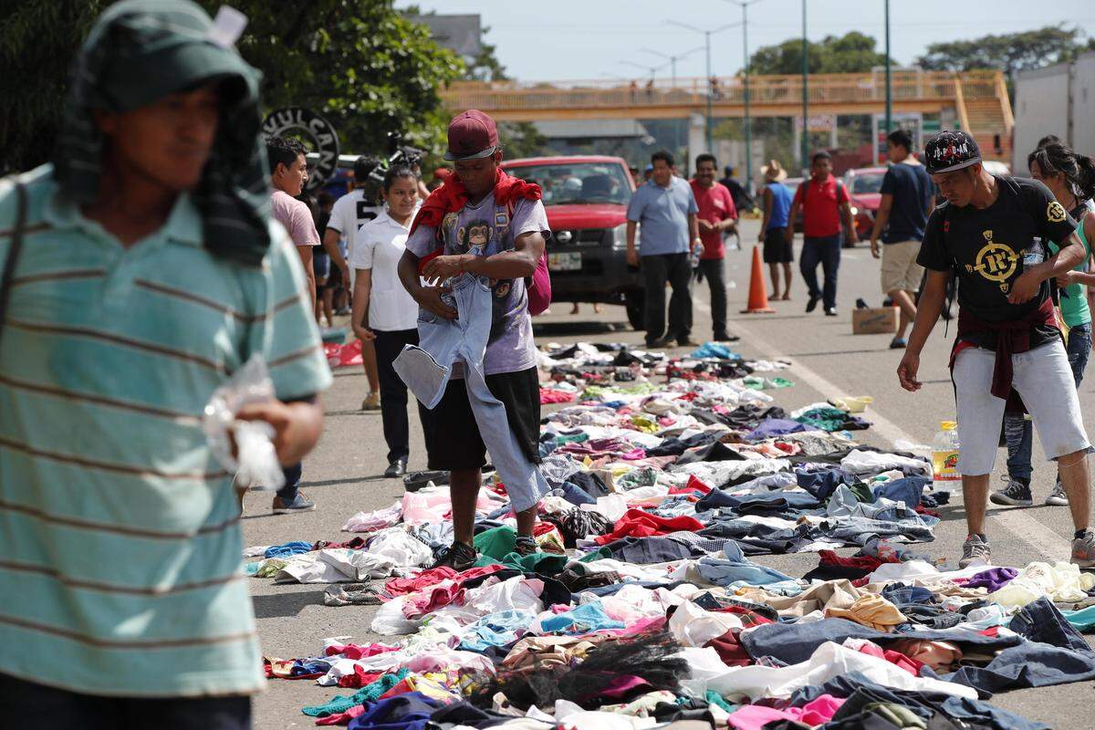 Migrantes hondureños seleccionan ropa que ha sido colocada a lo largo de la carretera por ciudadanos mexicanos durante su travesía hacia su objetivo, Estados Unidos.