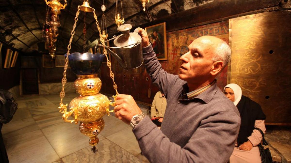 Un peregrino cristiano rellena de aceite una de las lamparillas en la Iglesia de la Natividad, en la ciudad de Belén.