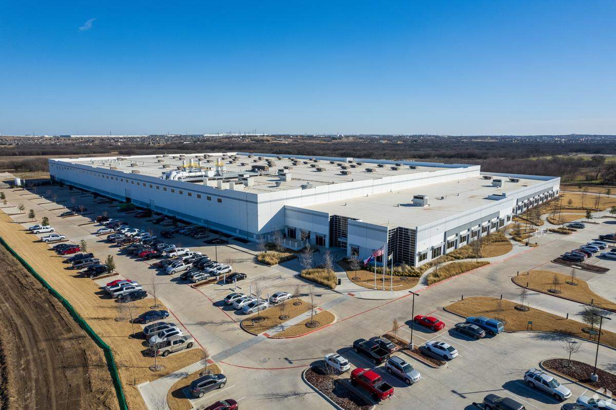 A large warehouse with cars parked around it.