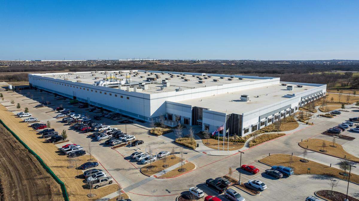 A large warehouse with cars parked around it.