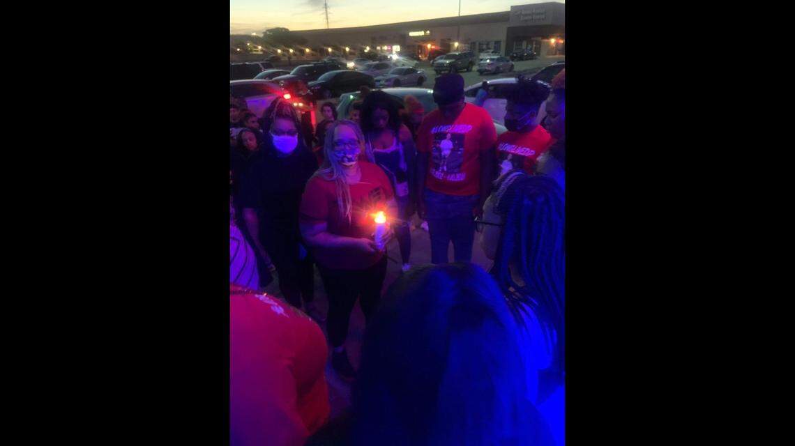 A crowd of people stand in the parking lot of the OK Mart on Hulen Bend Boulevard in south Fort Worth, TX, the location where a group of young men filmed a music video before a deadly shooting. Dominick Primes, 19, was killed in the shooting, and five others were injured, including two bystanders.