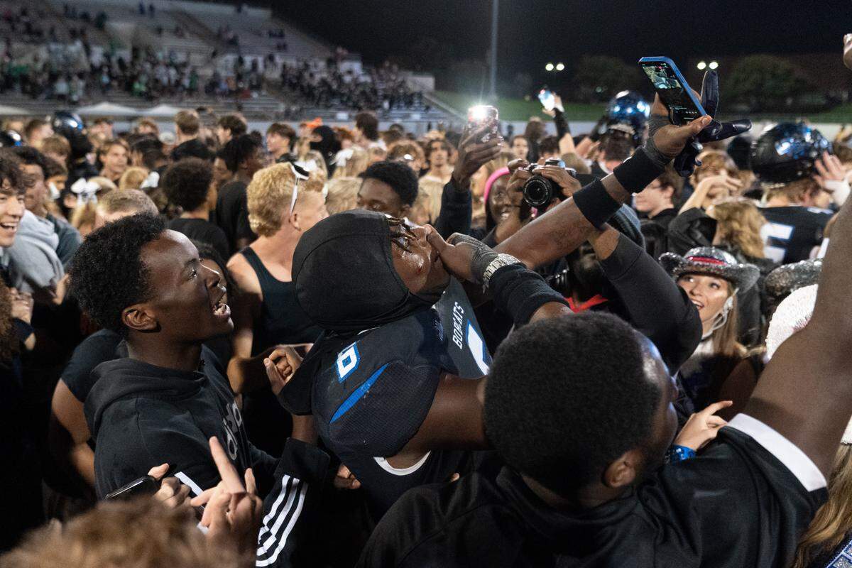 Trophy Club Nelson football players celebrate with fans on the field after a historic win over Southlake Carroll.