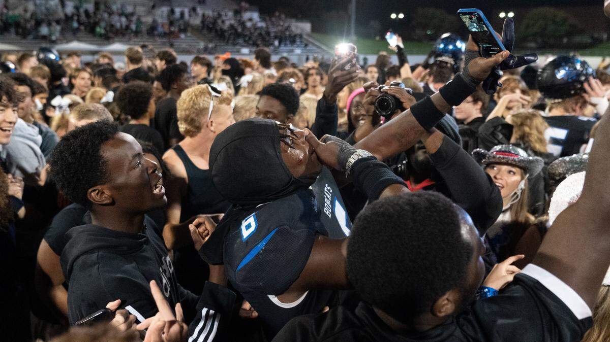 Trophy Club Nelson football players celebrate with fans on the field after a historic win over Southlake Carroll.