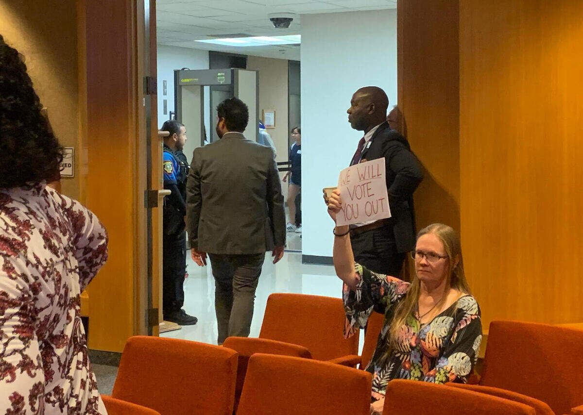 Saginaw resident Crystal Betts holds up a sign for County Judge Tim O’Hare to read as meeting attendees file out of the room due to the Tusday, June 17 meeting being canceled.
