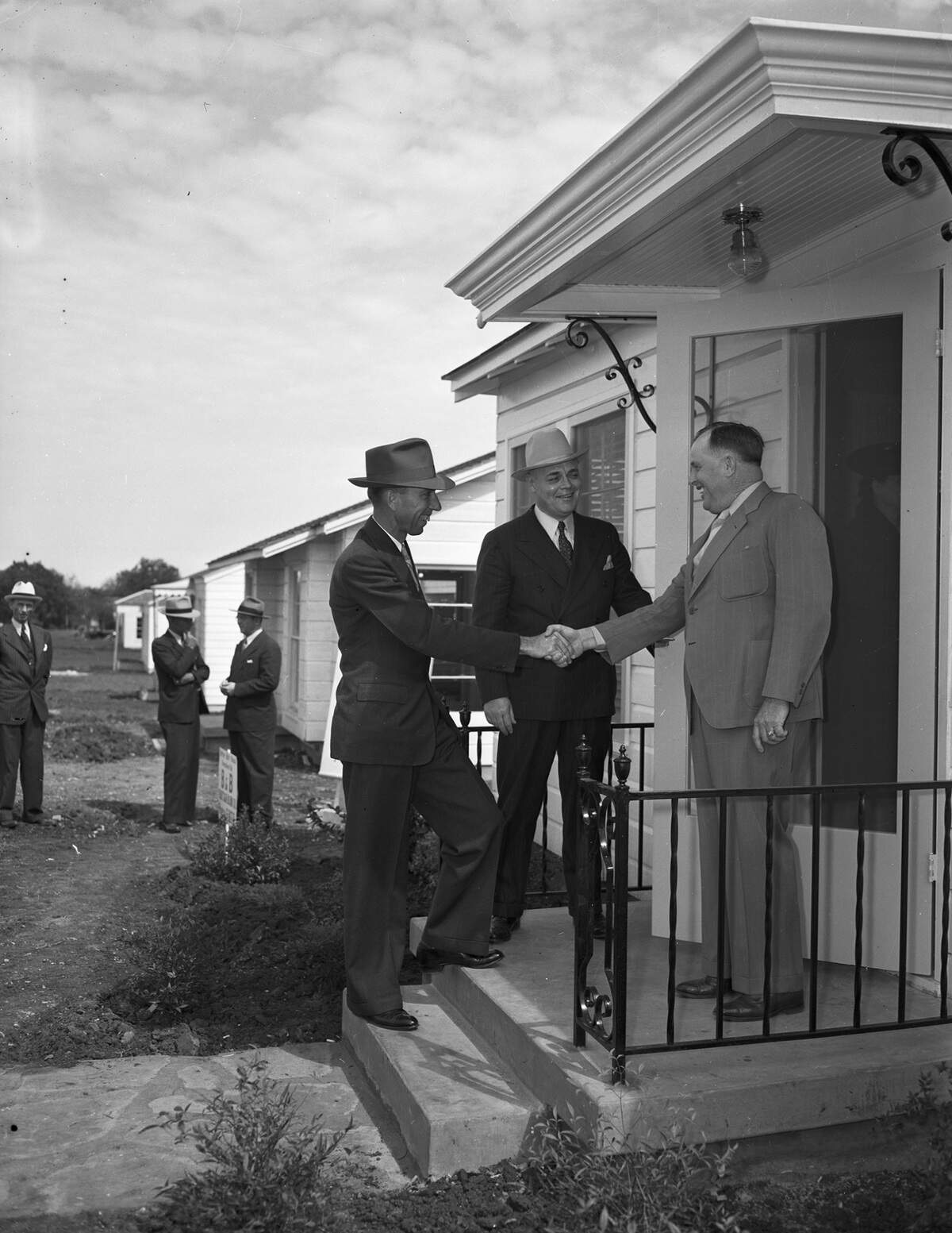 E. T. Stearns, left, regional director of the Federal Housing Administration, A. A. Lund, president of Chamber of Commerce, and Joe Driskell, right, inspect new houses in the 4000 block of Lovell Street. Built in June 1941, before the United States entered World War II, these affordable homes were part of more than 100 built in Factory Place that year.