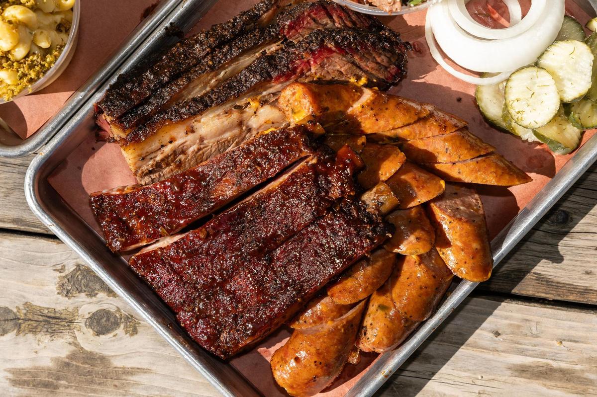 A platter with brisket, pork spare ribs, jalapeño cheese sausage, and a brisket eloté cup are paired with sides of collard greens, spicy smoked Mac & Cheese, banana pudding, and sliced bread at Panther City BBQ in Fort Worth. Panther City BBQ landed a spot on the Michelin recommended list making it one of the three restaurants Fort Worth to make the prestigious catalog.