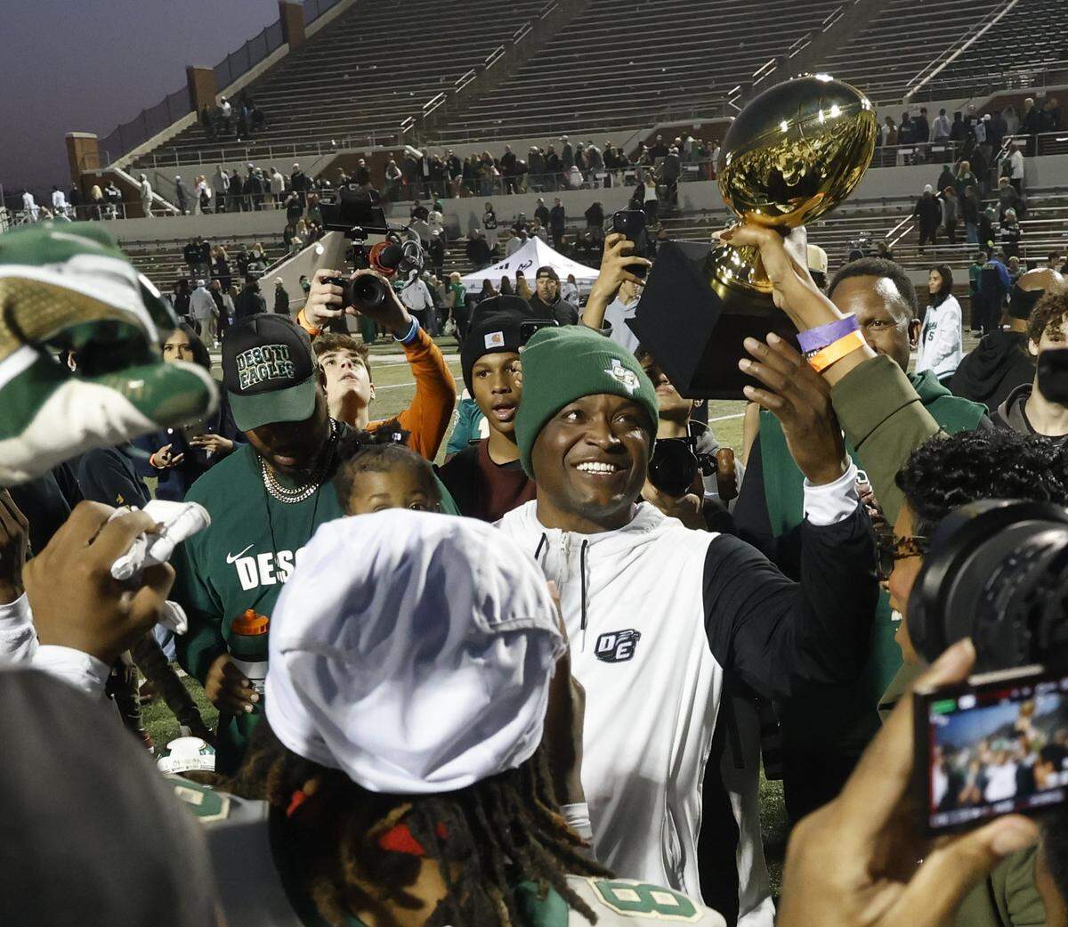 DeSoto head coach Claude Mathis receives the trophy from the DeSoto superintendent after his team defeated Southlake Carroll in a Class 6A Division II state semifinal Saturday at Newsom Stadium in Mansfield.